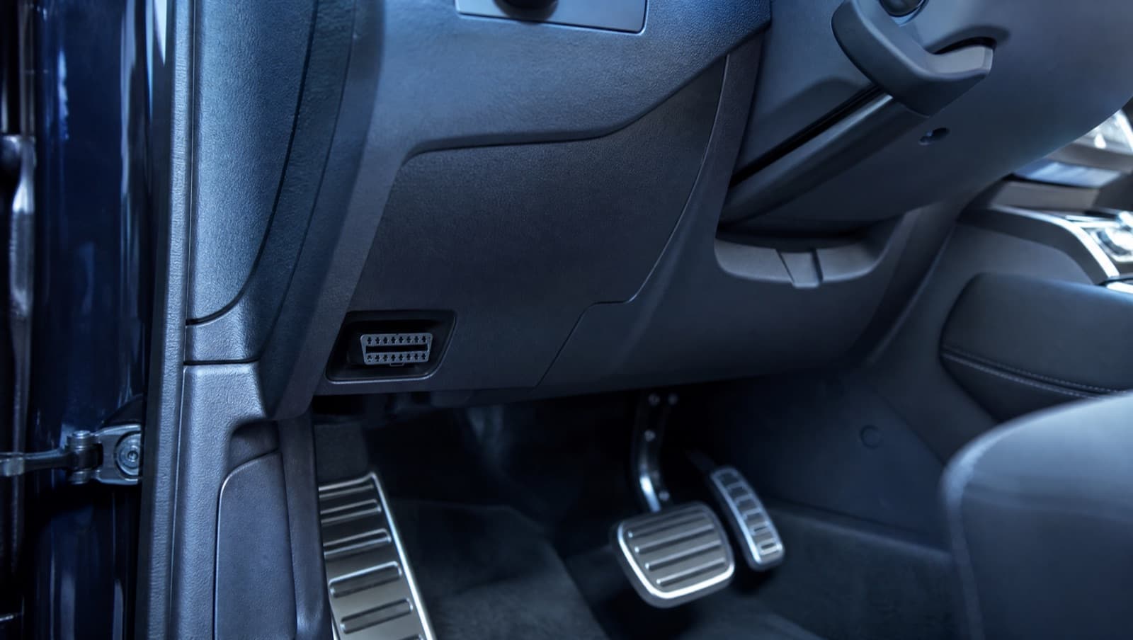 The OBD-II port location under a car dashboard near the steering column